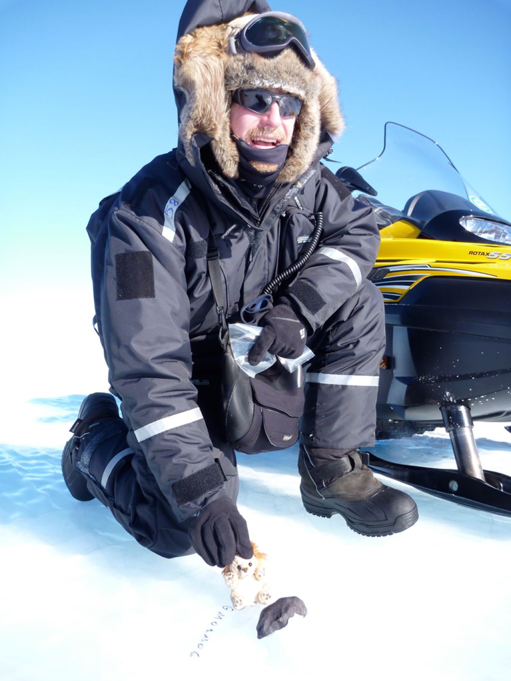 2010 laureate Steven Goderis photographed with a meteorite he found in a blue ice field. The team photographed meteorites next to a toy for size comparison. - © René Robert