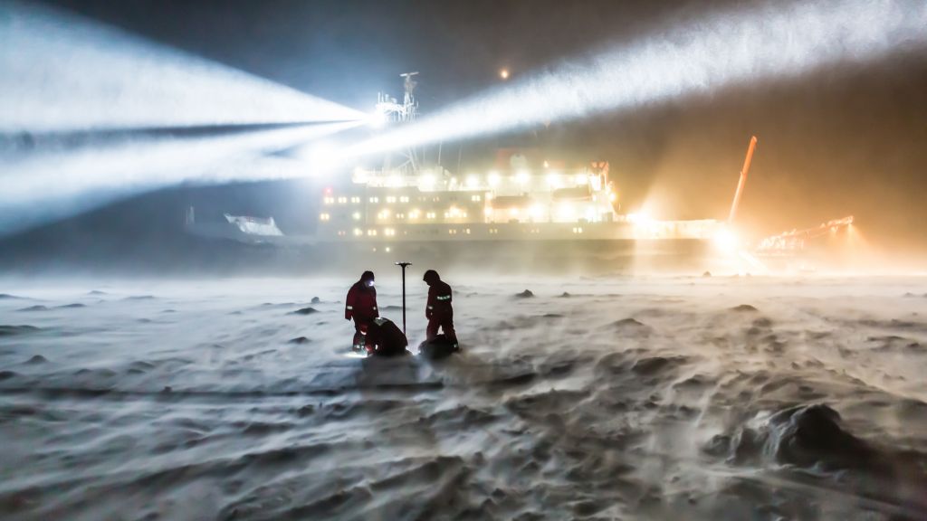 AWI sea ice physicists taking measurements on the sea ice in the darkness of the polar night.