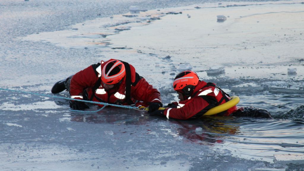 Members of the US Coast Guard stage a practice rescue in ice-covered waters.